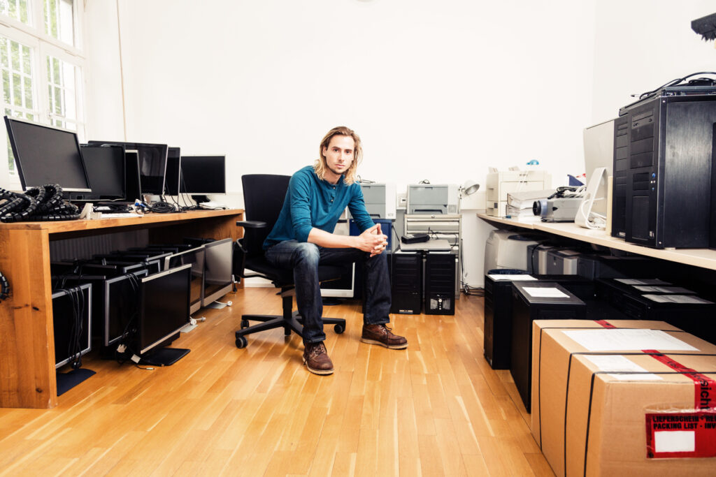 An IT professional sits with a variety of technology assets.