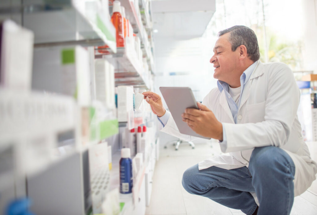 A man takes inventory on a tablet in a pharmacy.