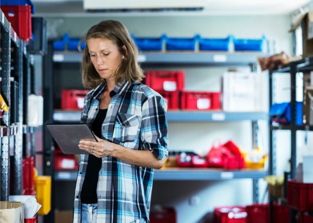 A woman calculates inventory turnover in an organized stockroom.